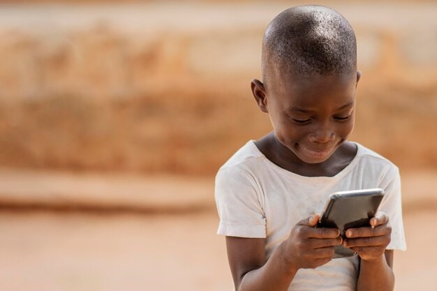 African boy holding a smartphone close to eyes